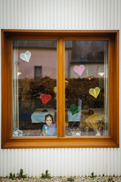 Birthday girl by the window. Kite paper hearts for decoration.