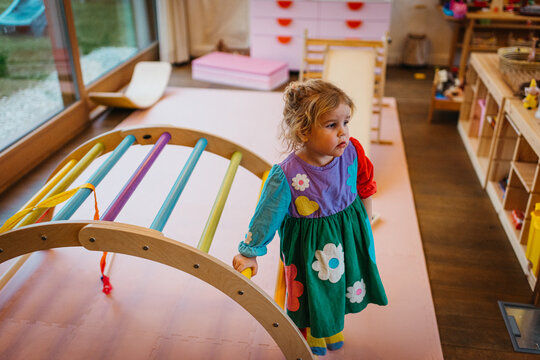 Girl in flower dress, standing in colorful playroom indoors