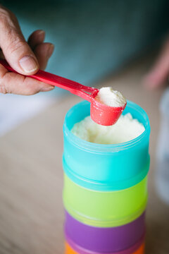 Old woman adding powder milk for baby in bottle 