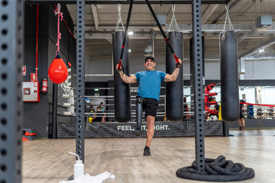 Man with artificial leg training with TRX straps