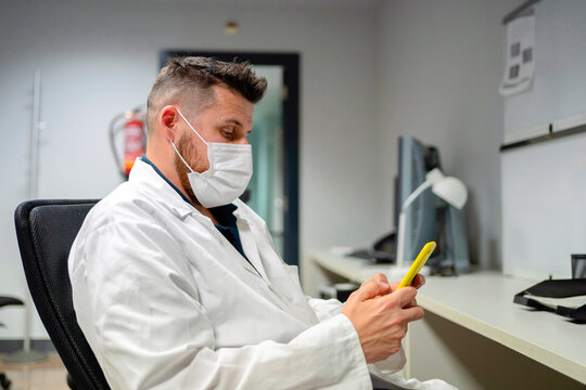 Exhausted doctor texting on mobile phone