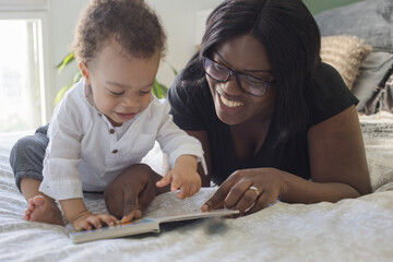 mother reading book to small child at home