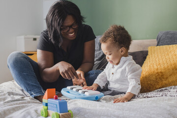 mother with small child playing with toys at home, small piano