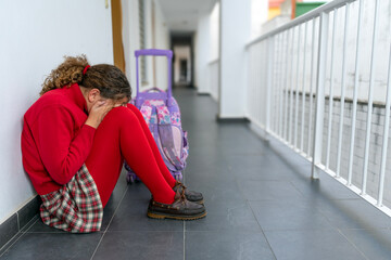 Girl in uniform with backpack alone crying in the school hallway. Bullying, adhd and autism.	 - obrazy, fototapety, plakaty