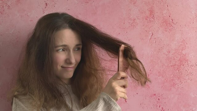 Woman struggling with frizzy hair combing, holding neem wood comb.