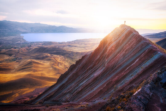 Person standing on epic mountain top in the sun