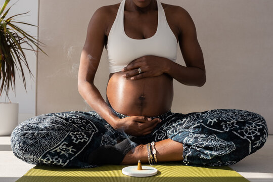 Crop pregnant woman meditating near incense - Powered by Adobe