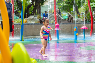 Adorable little girl enjoying in colorful city child water park outdoor activity