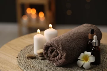 Foto op Plexiglas Spa composition. Rolled towel, cosmetic products, stones, burning candles and plumeria flower on table indoors, closeup © New Africa