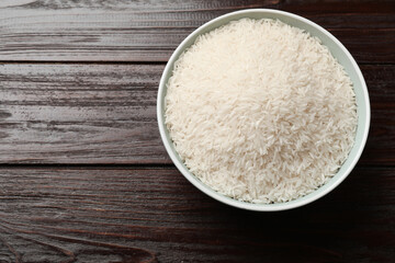 Fototapeta na wymiar Raw basmati rice in bowl on wooden table, top view. Space for text