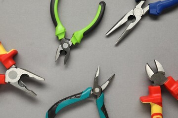 Different pliers on grey background, flat lay