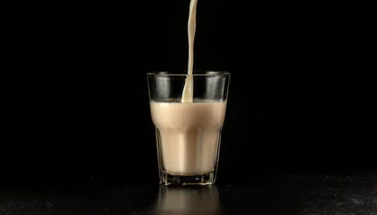 Fotobehang Milk being poured, almond milk, glass, black, close-up © NizuCaCi