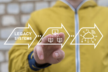 Businessman using virtual touch screen presses inscription: LEGACY SYSTEMS. Legacy System Business Technology Interoperability Modernization concept.