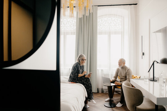 Mature married couple with gadgets in hotel room
