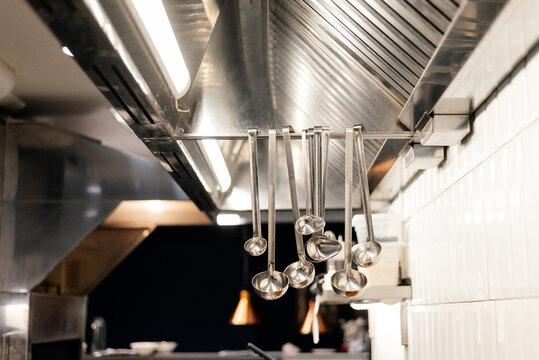 Soup ladles hanging on rail in restaurant kitchen
