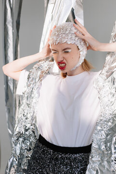 Irritated lady in trendy clothes against silver foil