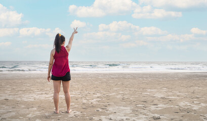 Summer beach vacation concept, happy woman raising hands up on sea beach background.