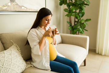 Healthy pregnant woman relaxing drinking tea on the couch