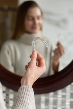  White Young Woman holding clear aligner on bathroom