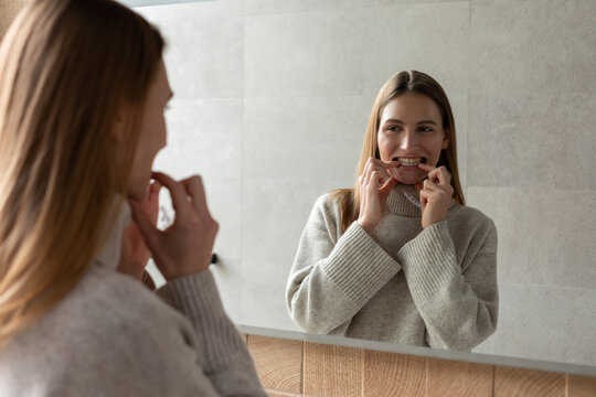White girl puts on a clear braces while looking in the mirror