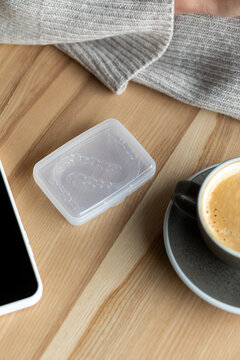 The transparent bracket box is on the table near the phone and coffee