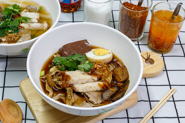 Guay Jub, Chinese roll noodle soup with boiled eggs and crispy pork in a white bowl.  it’s one of the top Thai Street Food