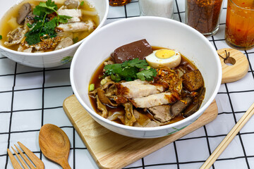 Guay Jub, Chinese roll noodle soup with boiled eggs and crispy pork in a white bowl.  it’s one of the top Thai Street Food