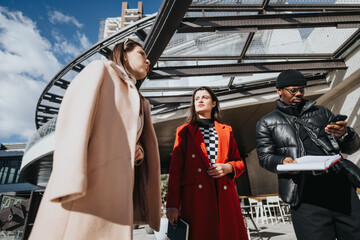 Multiracial businesspeople in stylish winter attire hold an informal meeting outside a modern office building under a bright blue sky.