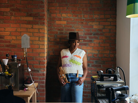  Black woman hat maker in a workshop space. 