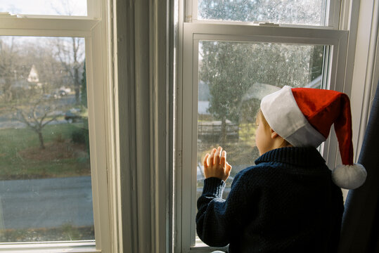 boy with santa hat looking out window