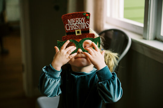 silly toddler in green dress with christmas glasses