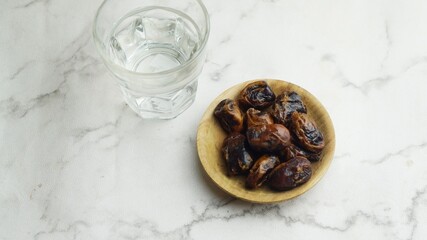 Kurma or dates fruit with glass of mineral water. Traditional Ramadan, iftar meal. Ramadan kareem fasting month concept