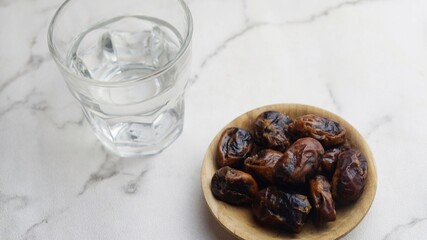 Kurma or dates fruit with glass of mineral water. Traditional Ramadan, iftar meal. Ramadan kareem fasting month concept