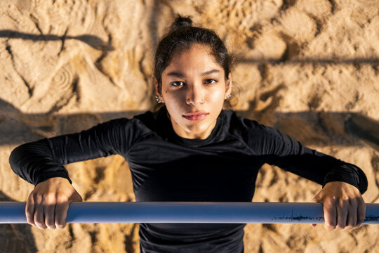 focused female athlete performing push-ups on horizontal bar