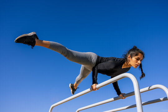 Focused female athlete performing handstand on parallel bars