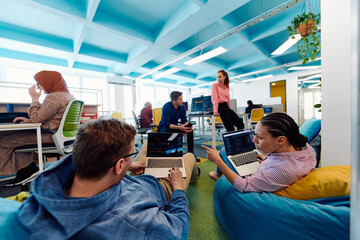 In a modern startup office, a diverse group of young and capable businesspeople engage in lively...