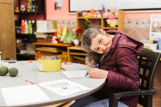 A woman with mental health issues making drawings in a classroom