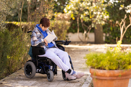 Woman with mobility difficulties reading a book at garden