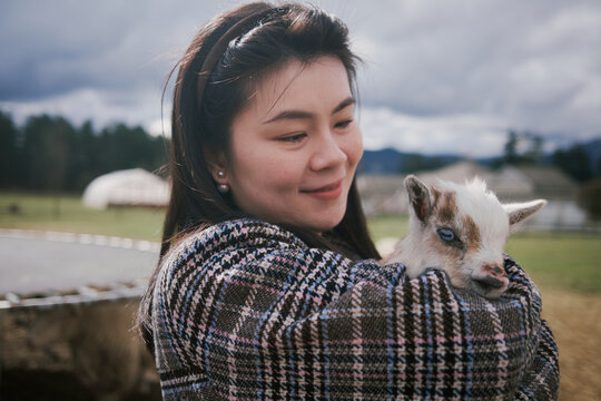 Cute Portrait Of Young Chinese Woman Holding A Baby Sheep.