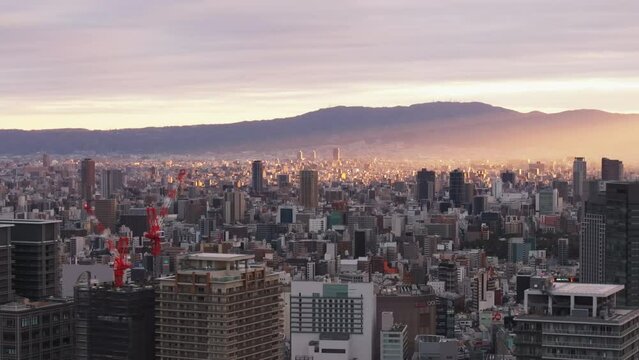Fly above metropolis in morning. Romantic view of sun rays shinning through clouds in sky. Osaka, Japan