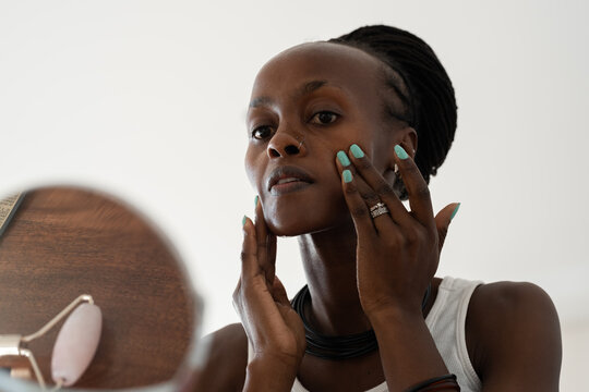 Black woman applying cosmetic product on face