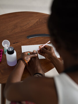 Black woman removing cuticles from toenails