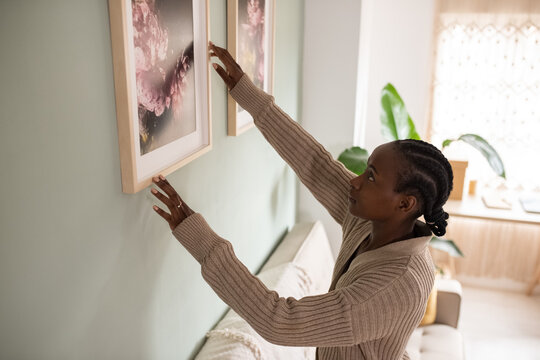 Black woman decorating wall with picture