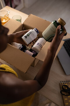 Black female taking wellness products from carton box