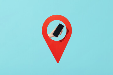 A person's hand holding cellphone in red pin pointer against blue