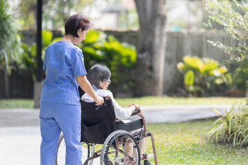 Elderly woman relaxing on wheelchair in backyard with caregiver.