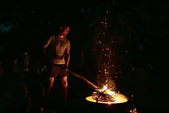 Man Tending Flames with a Long Stick