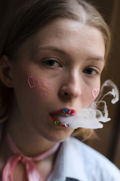Woman with unconventional make up blowing smoke