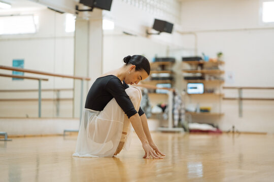 Slim ballet dancer practicing dance in spacious studio