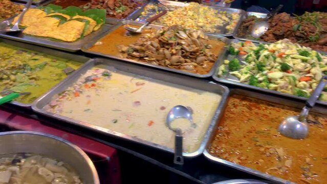 March 5, 2022. Thepprasit Night Market, Pattaya Thailand. Curries, soups and other wet Thai cuisine in metal serving dishes on a vendors table.